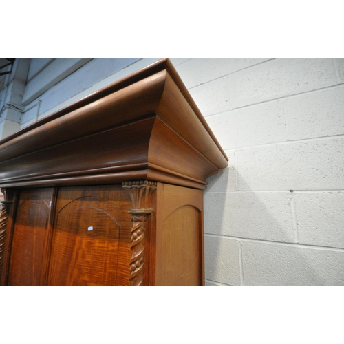 1263 - AN INDONESIAN HARDWOOD TWO DOOR WARDROBE, with a large over hanging cornice, twin twisted pillars, w... 