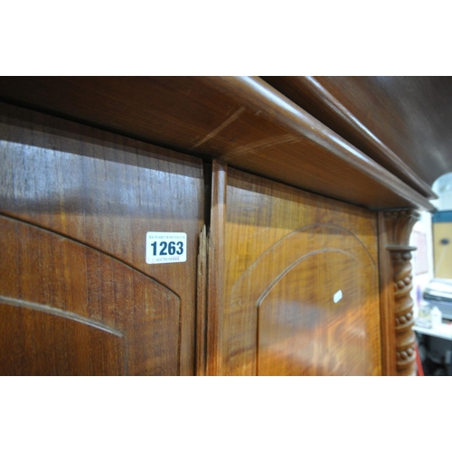 1263 - AN INDONESIAN HARDWOOD TWO DOOR WARDROBE, with a large over hanging cornice, twin twisted pillars, w... 