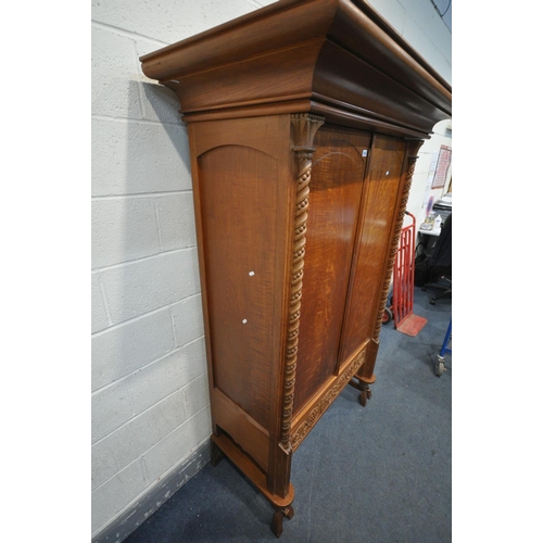 1263 - AN INDONESIAN HARDWOOD TWO DOOR WARDROBE, with a large over hanging cornice, twin twisted pillars, w... 