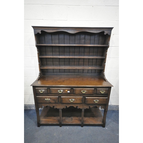 1284 - A REPRODUCTION OAK DRESSER, with a three tier plate rack, above a base with seven assorted drawers, ... 