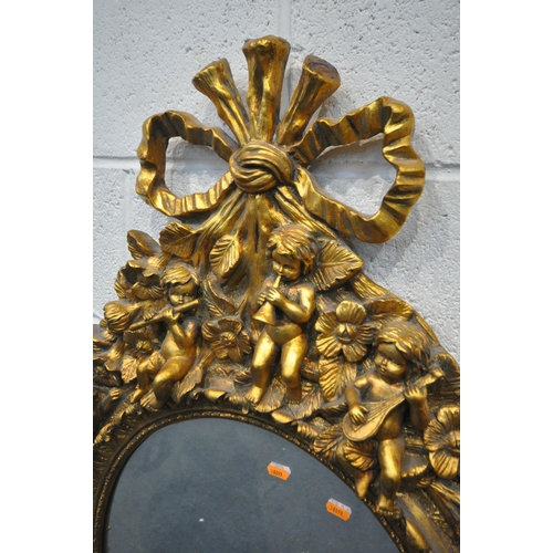 1334 - A 20TH CENTURY GILT OVAL WALL MIRROR, depicting a ribbon surmount, nine putto's with instruments, wi... 