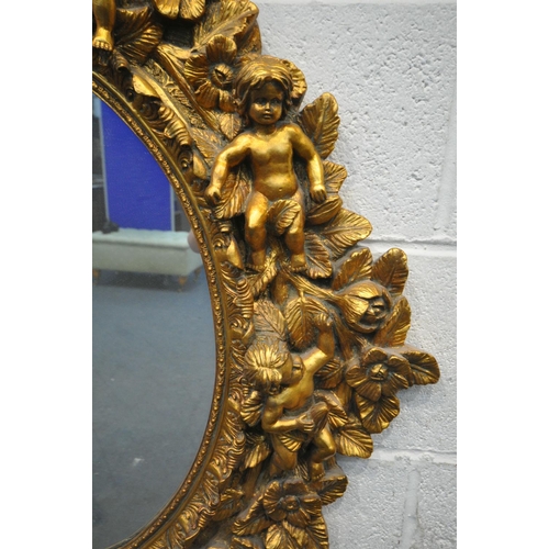 1334 - A 20TH CENTURY GILT OVAL WALL MIRROR, depicting a ribbon surmount, nine putto's with instruments, wi... 