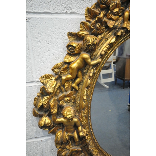 1334 - A 20TH CENTURY GILT OVAL WALL MIRROR, depicting a ribbon surmount, nine putto's with instruments, wi... 