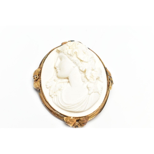 136 - A YELLOW METAL LAVA CAMEO BROOCH, the cameo carved to depict a lady in profile with floral detail to... 