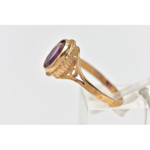 33 - A 9CT GOLD AMETHYST SINGLE STONE RING, the oval cut amethyst collet set, within a rope twist surroun... 