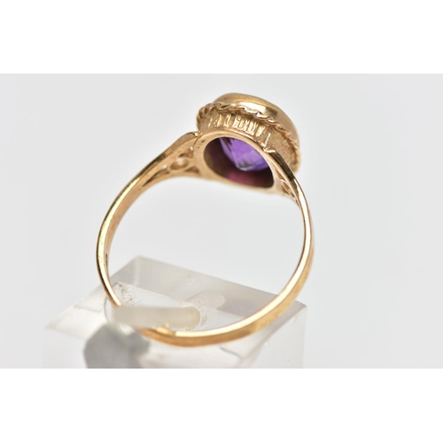 33 - A 9CT GOLD AMETHYST SINGLE STONE RING, the oval cut amethyst collet set, within a rope twist surroun... 