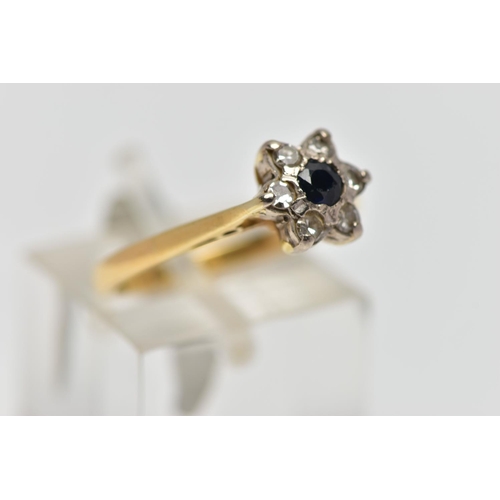 56 - A YELLOW AND WHITE METAL CLUSTER RING, a circular cut sapphire and six single cut diamonds prong set... 