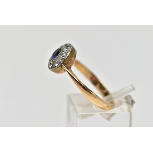 67 - A GEMSET CLUSTER RING, set with a synthetic sapphire, surrounded by colourless paste, to the tapered... 