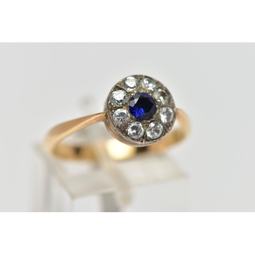 67 - A GEMSET CLUSTER RING, set with a synthetic sapphire, surrounded by colourless paste, to the tapered... 