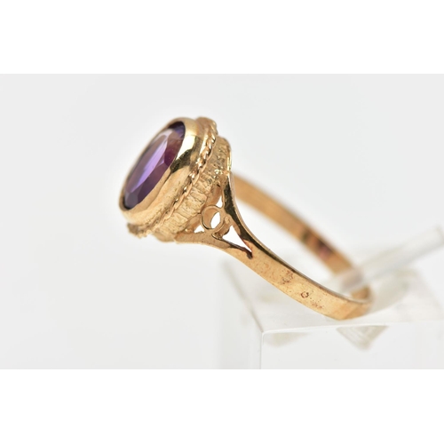 188 - A 9CT GOLD AMETHYST SINGLE STONE RING, the oval cut amethyst collet set, within a rope twist surroun... 