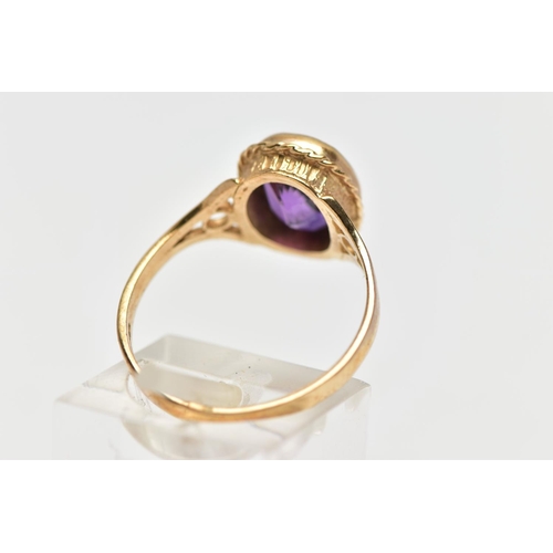 188 - A 9CT GOLD AMETHYST SINGLE STONE RING, the oval cut amethyst collet set, within a rope twist surroun... 