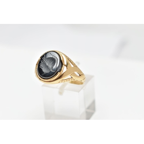 70 - A 9CT GOLD HEMATITE INTAGLIO SIGNET RING, of an oval form depicting a side profile of a soldier wear... 