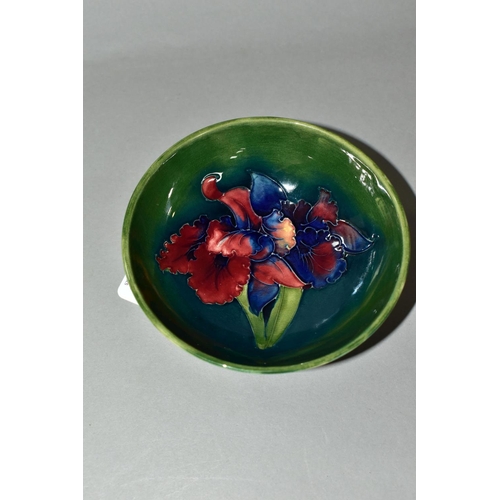 338 - A MOORCROFT POTTERY FOOTED BOWL, in Orchid pattern, with tube lined red and navy orchids on a blue g... 