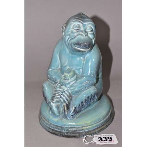 339 - A BESWICK MONKEY FIGURE, number 397, seated on a circular pottery base, holding a piece of fruit, pa... 