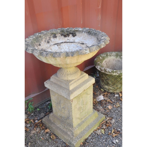 1007 - A PAIR OF MODRN COMPOSITE GARDEN URNS on square columns with pie crust top edges, baluster and flute... 