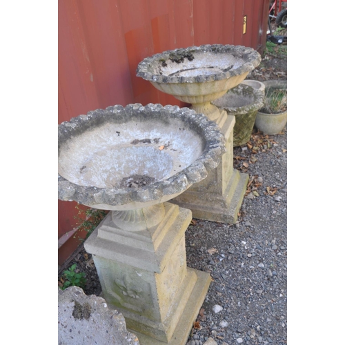 1007 - A PAIR OF MODRN COMPOSITE GARDEN URNS on square columns with pie crust top edges, baluster and flute... 