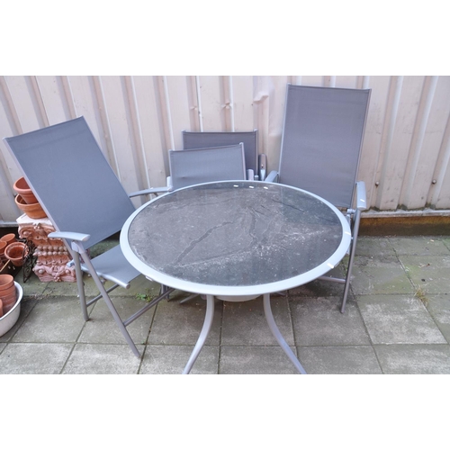 1031 - A METAL FRAMED AND SMOKED GLASS GARDEN TABLE diameter 100cm and four similar folding chairs (Conditi... 