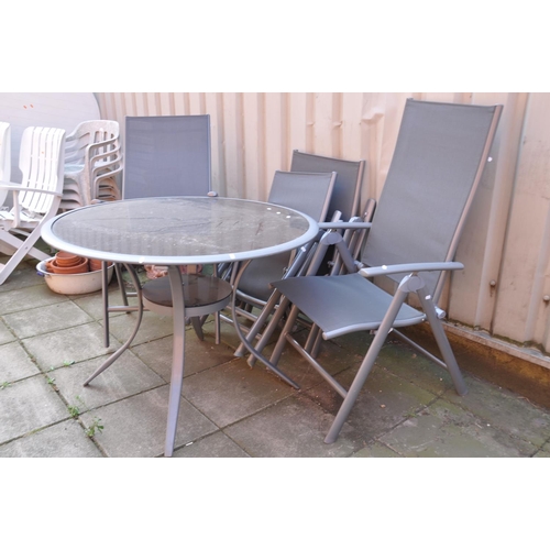 1031 - A METAL FRAMED AND SMOKED GLASS GARDEN TABLE diameter 100cm and four similar folding chairs (Conditi... 