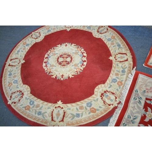 1260 - A RED GROUND CIRCULAR RUG, with cream border and centre, diameter 185cm, and two similar rectangular... 