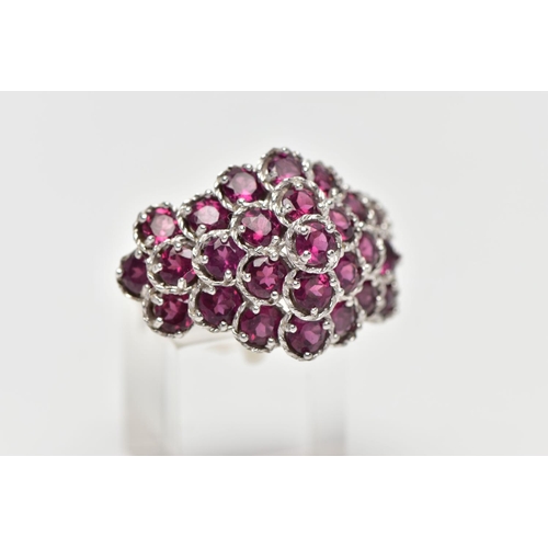 21 - A SILVER TOURMALINE COCKTAIL RING, designed as a cluster of raised circular cut pink tourmalines, cl... 