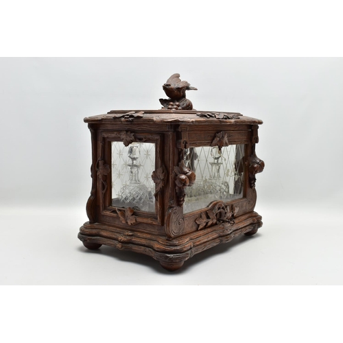 219 - A LATE 19TH CENTURY AND LATER BLACK FOREST CARVED AND STAINED WALNUT TANTALUS, carved surmount of a ... 