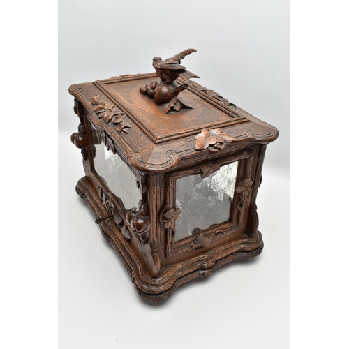 219 - A LATE 19TH CENTURY AND LATER BLACK FOREST CARVED AND STAINED WALNUT TANTALUS, carved surmount of a ... 