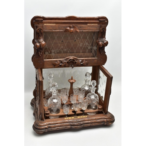 219 - A LATE 19TH CENTURY AND LATER BLACK FOREST CARVED AND STAINED WALNUT TANTALUS, carved surmount of a ... 