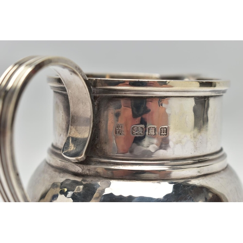 34 - A GEORGE V SILVER JUG OF SQUAT BALUSTER FORM, the S scroll reeded handle on a planished body, makers... 