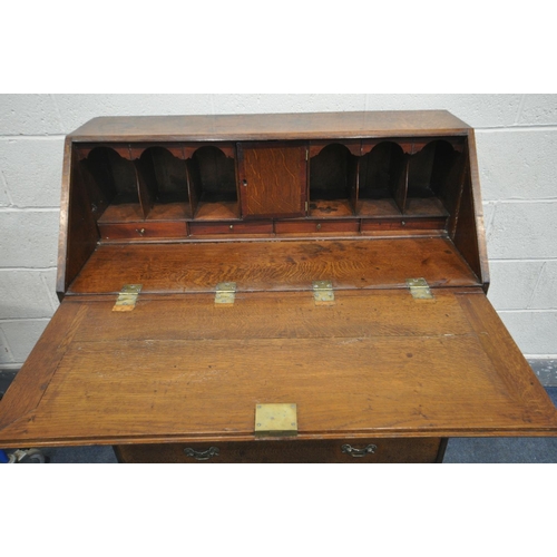 1254 - A GEORGIAN OAK AND MAHOGANY CROSSBANDED BUREAU, the fall front enclosing a fitted interior, above fo... 