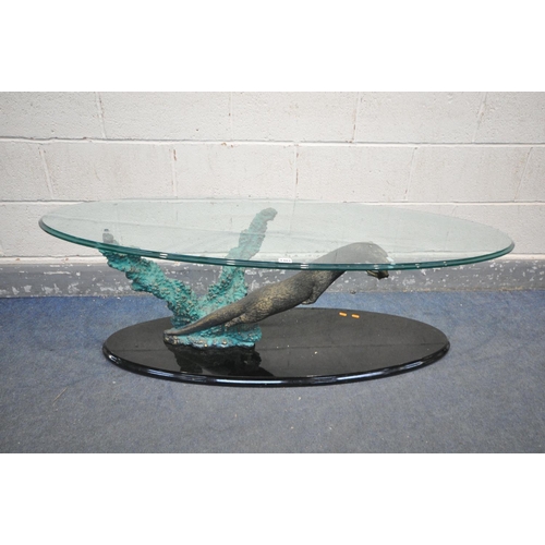 1401 - AN GLASS TOP OVAL COFFEE TABLE, the base in the form of an otter hunting a fish, length 140cm x dept... 