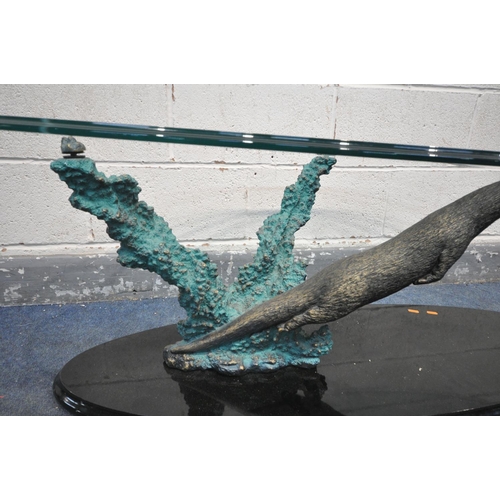 1401 - AN GLASS TOP OVAL COFFEE TABLE, the base in the form of an otter hunting a fish, length 140cm x dept... 