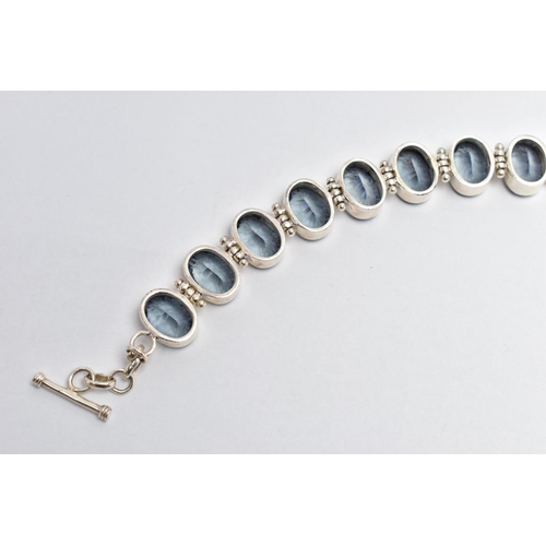 15 - A SILVER IOLITE BRACELET, the oval cut iolites collet set, with hinged spacers, to the circular link... 