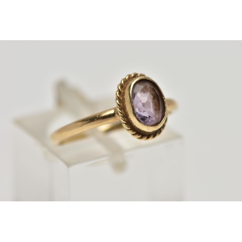 20 - A 9CT GOLD AMETHYST SINGLE STONE RING, the oval cut amethyst within a collet setting, to the rope tw... 