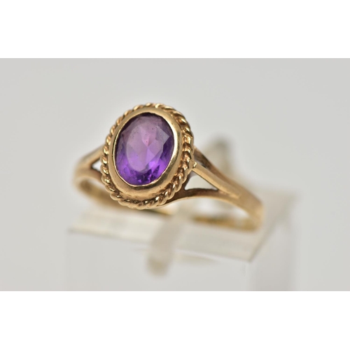 21 - A 9CT GOLD AMETHYST SINGLE STONE RING, the oval cut amethyst within a collet setting, to the openwor... 