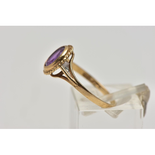 21 - A 9CT GOLD AMETHYST SINGLE STONE RING, the oval cut amethyst within a collet setting, to the openwor... 