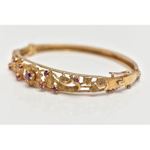 59 - A 9CT GOLD FLORAL BANGLE, a yellow gold oval form hinged bangle, open work textured detail set with ... 