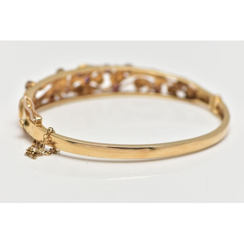 59 - A 9CT GOLD FLORAL BANGLE, a yellow gold oval form hinged bangle, open work textured detail set with ... 