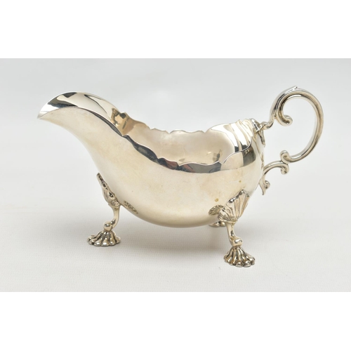 1055A - A GEORGE V SILVER SAUCEBOAT, wavy rim, 'C' scroll handle, on three cabriole legs with shell knees an... 