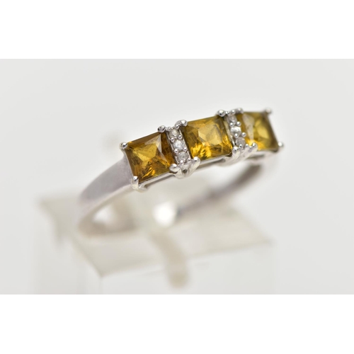 32 - A 9CT WHITE GOLD GEM SET RING, designed with a row of three square yellowish/green stones assessed a... 