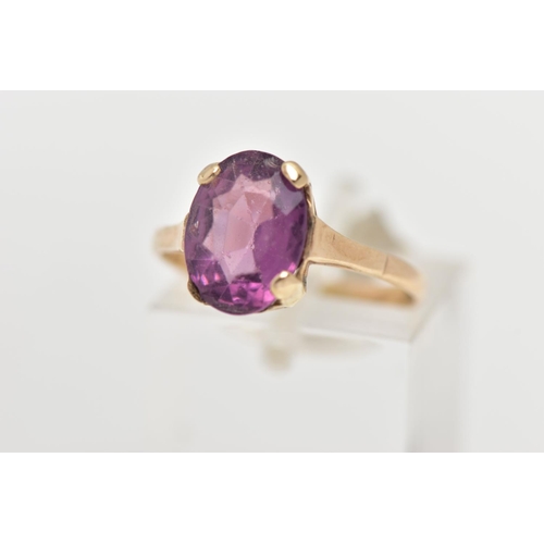 36 - A YELLOW METAL AMETHYST RING, an oval cut amethyst four claw set in a yellow metal mount, polished b... 