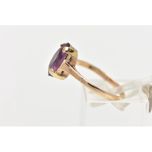 36 - A YELLOW METAL AMETHYST RING, an oval cut amethyst four claw set in a yellow metal mount, polished b... 