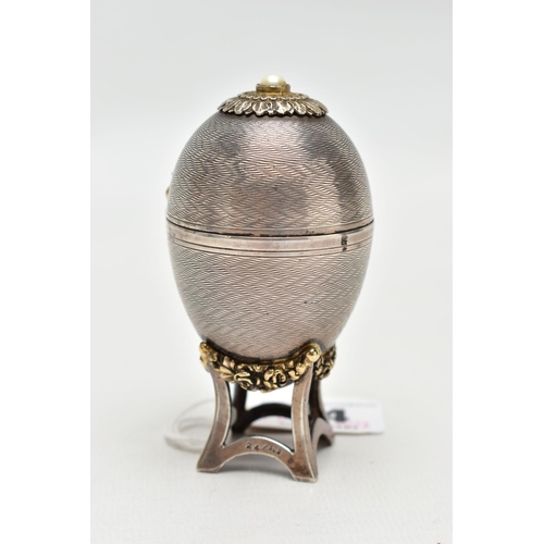 64 - A 'ST JAMES HOUSE COMPANY' SILVER EASTER EGG CLOCK,  featuring a small round clock with a white dial... 