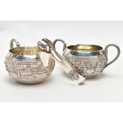 74 - A WHITE METAL SUGAR BOWL, CREAMER AND PAIR OF SUGAR TONGS, the sugar bowl and creamer each decorated... 