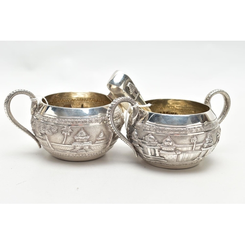 74 - A WHITE METAL SUGAR BOWL, CREAMER AND PAIR OF SUGAR TONGS, the sugar bowl and creamer each decorated... 