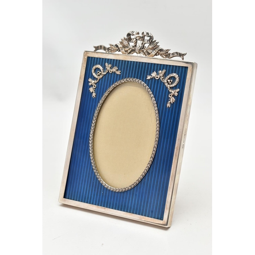 84 - A SILVER GARLAND PHOTOFRAME, of a rectangular form, oval aperture with a deep blue patterned surroun... 