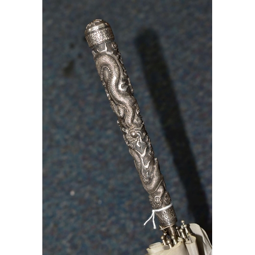 340 - A CHINESE SILVER AND GREY UMBRELLA/PARASOL, with a white metal handle embossed with Dragons, length ... 