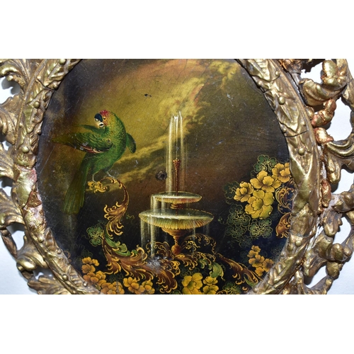 437 - A 19TH CENTURY GILT FRAMED OVAL PAPIER MACHÉ PAINTING, of an exotic parrot, fountain and foliate des... 