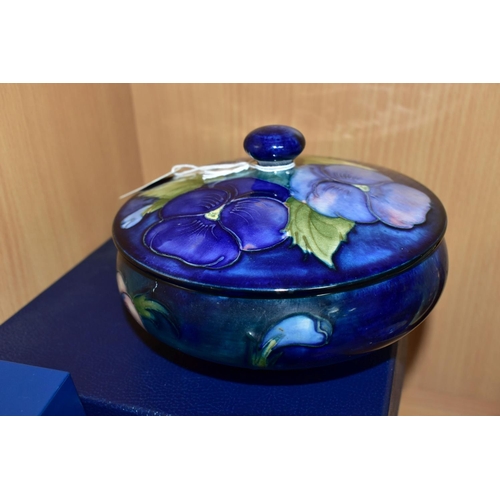 450 - A BOXED MOORCROFT POTTERY 'BLUE PANSY' COVERED BOWL, of shallow squat form, having tube lined blue a... 