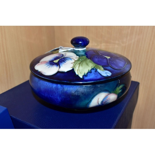 450 - A BOXED MOORCROFT POTTERY 'BLUE PANSY' COVERED BOWL, of shallow squat form, having tube lined blue a... 