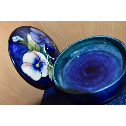 450 - A BOXED MOORCROFT POTTERY 'BLUE PANSY' COVERED BOWL, of shallow squat form, having tube lined blue a... 